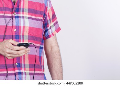 Average Man Wearing A Shirt And Earphones, Using His Mobile Phone.