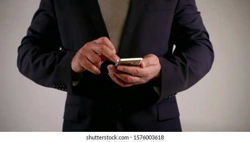 The Average Plan Of Men's Hands With A Smartphone. A Man In A Dark Jacket Holds The Phone In Front Of Him And Runs His Fingers Over The Screen. White Background