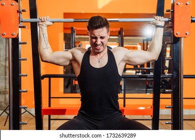 Average Plan Of Muscular Man Wearing Black Sportswear, Training Muscles, Biceps And Triceps - With An Effort He Lifting The Bar. Fitness And Sport. Healthy Lifestyle Concept