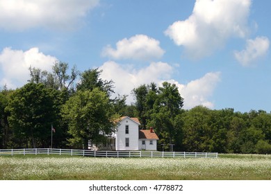 Average Rural American Home In Summer Under A Blue Sky With A Field Of Flowers In Front