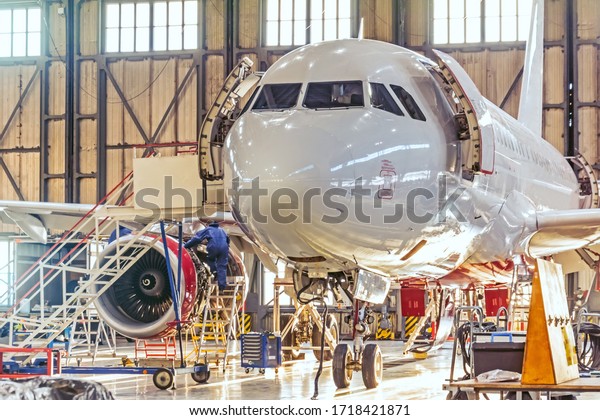 Aviation hangar and repairable\
passenger aircraft. Work mechanics on maintenance\
parts