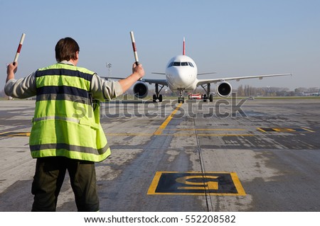 Aviation marshaller meets airplane at the airport. Airport worker. Modern airport.