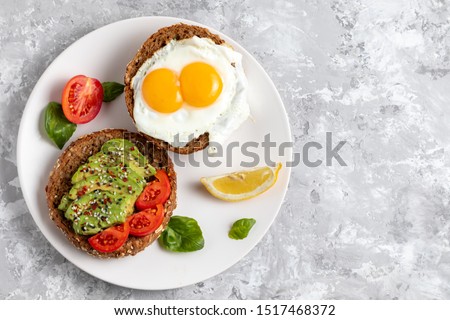 Avicado toast. Egg sandwich appetizer. Top view of balanced brunch food with rye bread. Healthy vegetarian dish recipe with tomato, basil and chili. Gourmet snack. Fitness vegan burger. Copy space