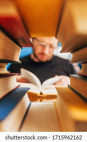 An avid reader with a book in defocus in a frame of books - the concept of literature and training