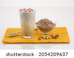 Avil milk, malabar special shake which is  arranged in a dessert glass with rice flakes and nuts placed besides it , on a yellow napkin.