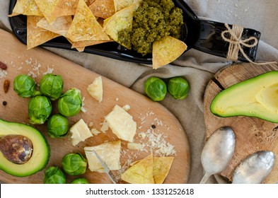 Avocado, Brussel Sprouts, Parmesan Cheese And Chips With Pesto Sauce On Unusual Serving Plate. Snaks And Healthy Food Concept. 