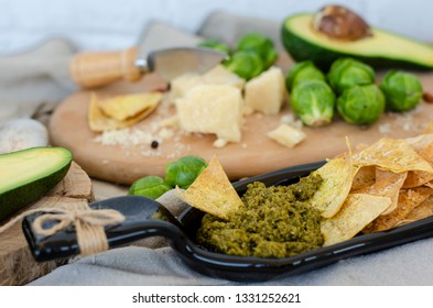 Avocado, Brussel Sprouts, Parmesan Cheese And Chips With Pesto Sauce On Unusual Serving Plate. Snaks And Healthy Food Concept. 