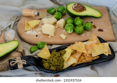 Avocado, Brussel Sprouts, Parmesan Cheese And Chips With Pesto Sauce On Unusual Serving Plate. Snaks And Healthy Food Concept. 