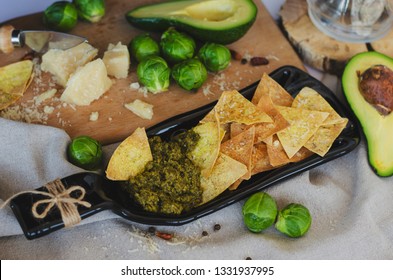 Avocado, Brussel Sprouts, Parmesan Cheese And Chips With Pesto Sauce On Unusual Serving Plate. Top View