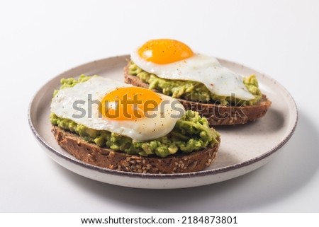 Avocado egg sandwich with a glass of water. Healthy light breakfast concept. Whole grain toasts with mashed avocado and fried eggs