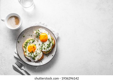 Avocado Egg Sandwiches for healthy breakfast. Whole grain toasts with mashed avocado, fried eggs and organic microgreens on white table, copy space. - Powered by Shutterstock