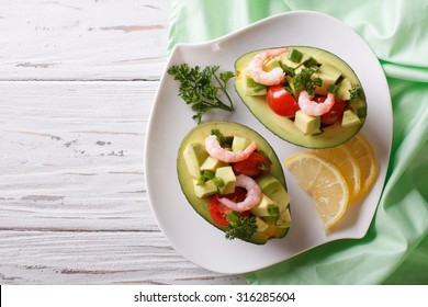 Avocado Filled With Shrimp Salad And Vegetables On A Plate. Horizontal View From Above
