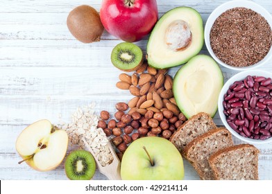 Avocado, Flax Seeds, Whole Grain Bread, Kiwi Fruit, Nuts, Oatmeal, Beans And Apples On Wooden Boards. Healthy Food. Top View