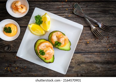 Avocado with fried prawns on and cocktail sauce on wooden table