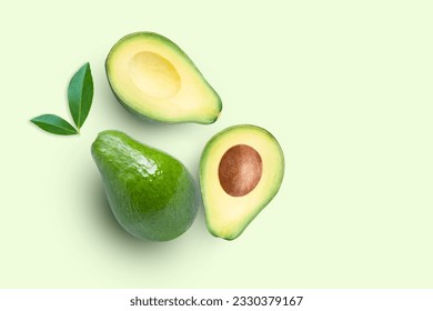 Avocado fruit and cut in half sliced with green leaf isolated on green color background. Top view. Flat lay. Copy space.