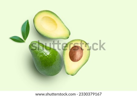 Avocado fruit and cut in half sliced with green leaf isolated on green color background. Top view. Flat lay. Copy space.