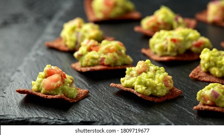 Avocado Guacamole With Chipotle And Poblano Whole Grain Tortilla Chips On Rustic Stone Board