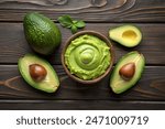 Avocado with guacamole sauce on a dark wood background. Half and whole avocados are close. View from above. Copy space