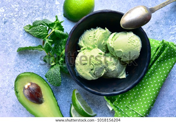 Avocado lime mint ice\
cream in a black bowl over light grey slate, stone or concrete\
background.Top view .
