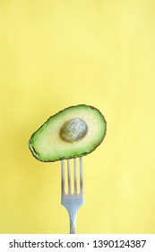 Avocado on a fork. Yellow background with empty space	