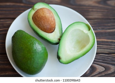 Avocado on old wooden table.Halfs on wooden bowl. Fruits healthy food concept. - Shutterstock ID 1100398643