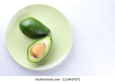Avocado on white background, sliced avocado on green plate, vegetarian food, mexican food, tropical fruit for breakfast, copy space