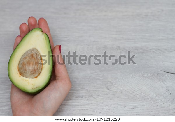 avocado on wood table in hand\
women