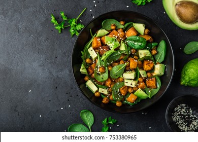 Avocado, quinoa, roasted sweet potato, spinach and chickpeas salad in black bowl. Top view, copy space - Shutterstock ID 753380965