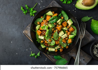Avocado, quinoa, roasted sweet potato, spinach and chickpeas salad in black bowl. Top view, copy space - Shutterstock ID 757986865