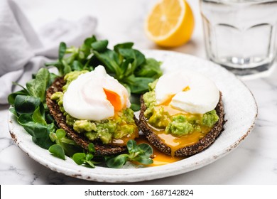 Avocado Rye Bread Toast With Poached Egg On Plate. Healthy Appetizer, Breakfast, Lunch Or Snack. Runny Egg Yolk