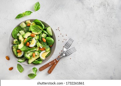 Avocado Salad With Boiled Eggs, Broccoli, Spinach And Almond Nuts In Bowl On White Background. Top View.