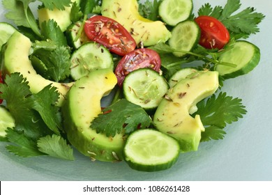 Avocado salad with cucumbers, cherry tomatoes, coriander leaves, closeup, on a glass plate. - Powered by Shutterstock