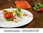 Avocado Salmon Tartar. Seafood appetizer. Avocado salmon tartar starter plate served with fresh vegetable salad.