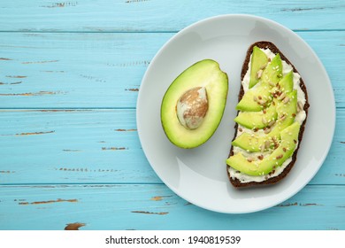 Avocado Sandwich On Dark Rye Bread Made With Half Of Avocado On Blue Background. Top View