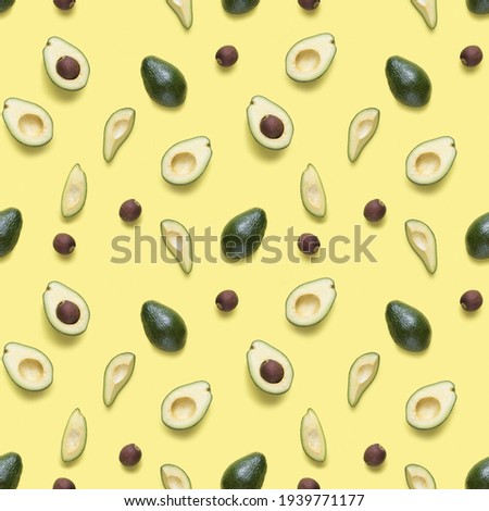 Avocado seamless pattern. Background made from isolated avocado pieces on yellow background. Flat lay of whole and half avocados, avacado pieces and seeds. 