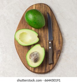 Avocado sliced in half and knife on wooden board. Top view. - Shutterstock ID 664430191