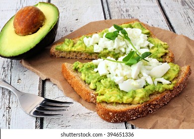 Avocado Toast With Egg Whites And Pea Shoots On Paper Against A White Wood Background