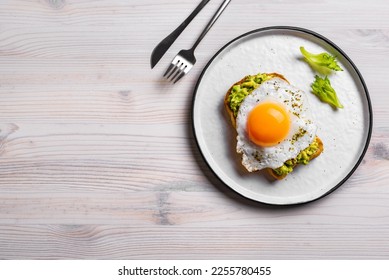 Avocado toast with fried egg on wooden table, top view, copy space. Toasted bread with avocado and egg for healthy breakfast. - Powered by Shutterstock