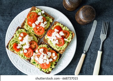 Avocado toast. Healthy toast with avocado mash, cherry tomatoes and crumbled feta cheese on a plate. Table top view. Healthy food, vegetarian food concept - Powered by Shutterstock