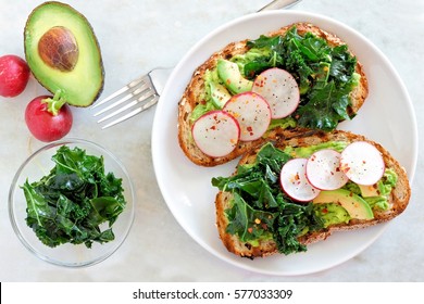 Avocado Toast With Kale And Radish On Whole Grain Bread, Overhead Scene On Marble