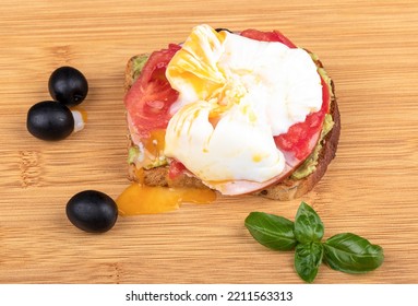 Avocado Toast With Melted Poached Egg Yolk On A Cutting Board. Top View.