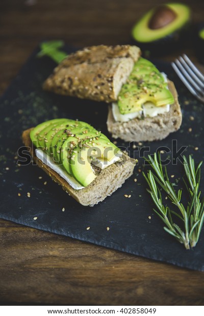 Avocado toast on\
wooden background. Breakfast with toast avocado, vegetarian food,\
healthy diet concept.