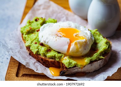 Avocado toast with poached egg on a wooden board. Breakfast concept. - Shutterstock ID 1907972692