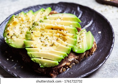 Avocado Toast With Rye Bread And Hemp Seeds On A Black Plate. Healthy Vegan Food Concept.