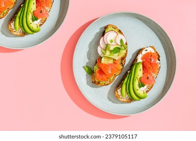 Avocado toast with salmon and soft cheese on a plate. Top view, hard light. - Powered by Shutterstock