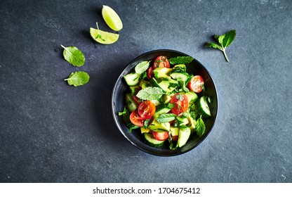 Avocado, tomato and cucumber salad with fresh herbs on dark stone background. Healthy summertime salad. Copy space - Powered by Shutterstock