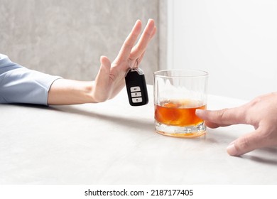 Avoid drinking and driving. A woman's hand trying to deny the alcohol is gripping a car key.