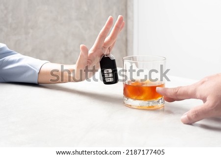 Avoid drinking and driving. A woman's hand trying to deny the alcohol is gripping a car key.
