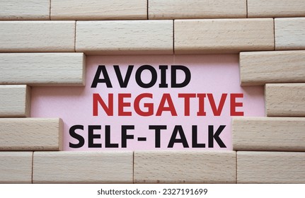 Avoid negative self-talk symbol. Concept words Avoid negative self-talk on wooden blocks. Beautiful pink background. Business and Avoid negative self-talk concept. Copy space.