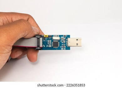 An AVR microcontroller USB downloader held in one hand.